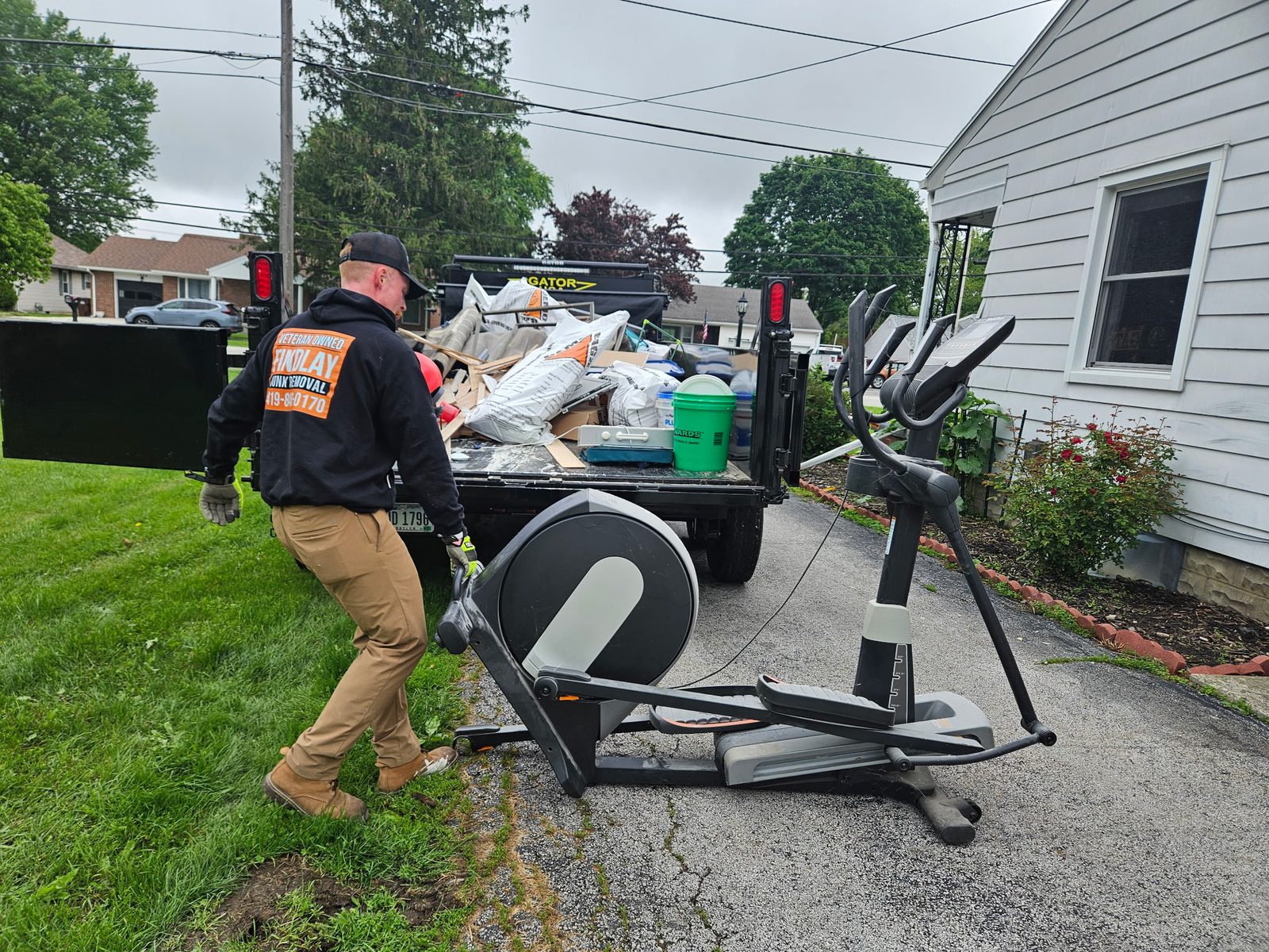 Findlay Junk Removal crew hauling an elliptical from a driveway
